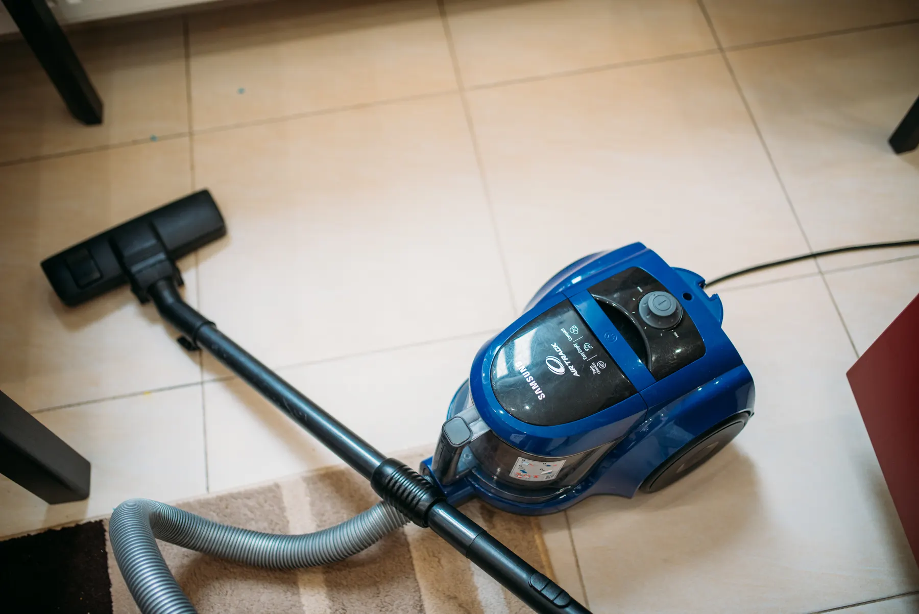 Vacuum cleaner on a tiled living room floor mid-clean